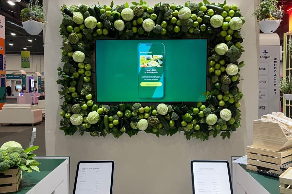 digital display monitor on a wall with green plants framing it.