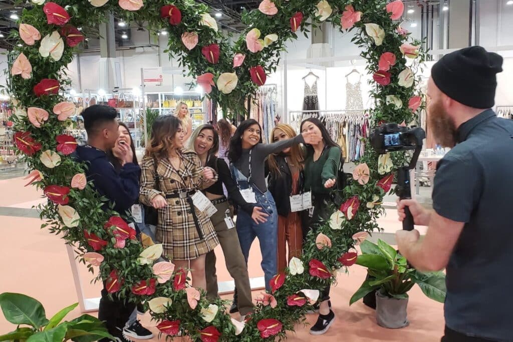 group of people posing behind a heart shaped floral sculpture being photographed