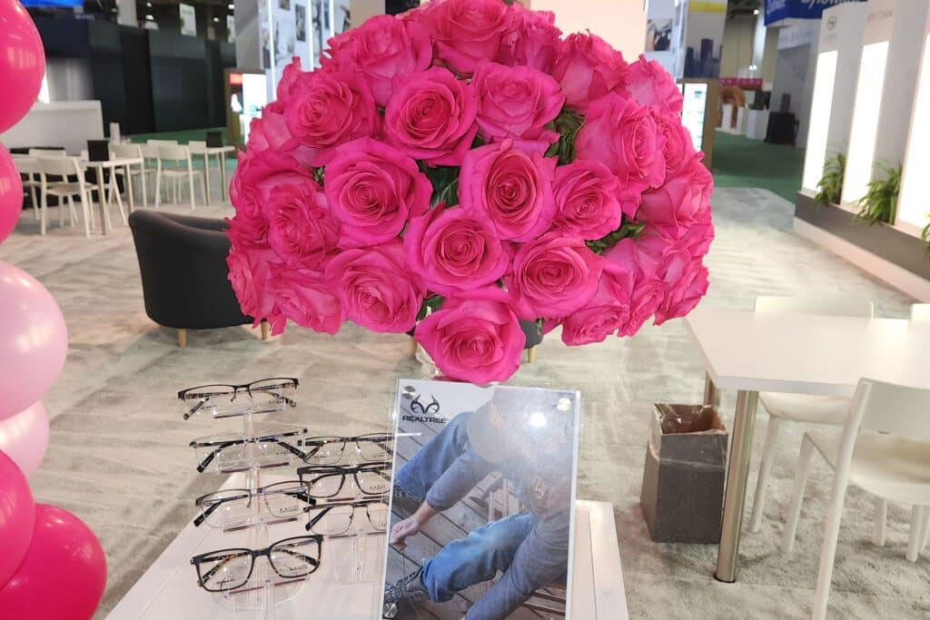 vase of two dozen pink roses next to a table with eyeglasses