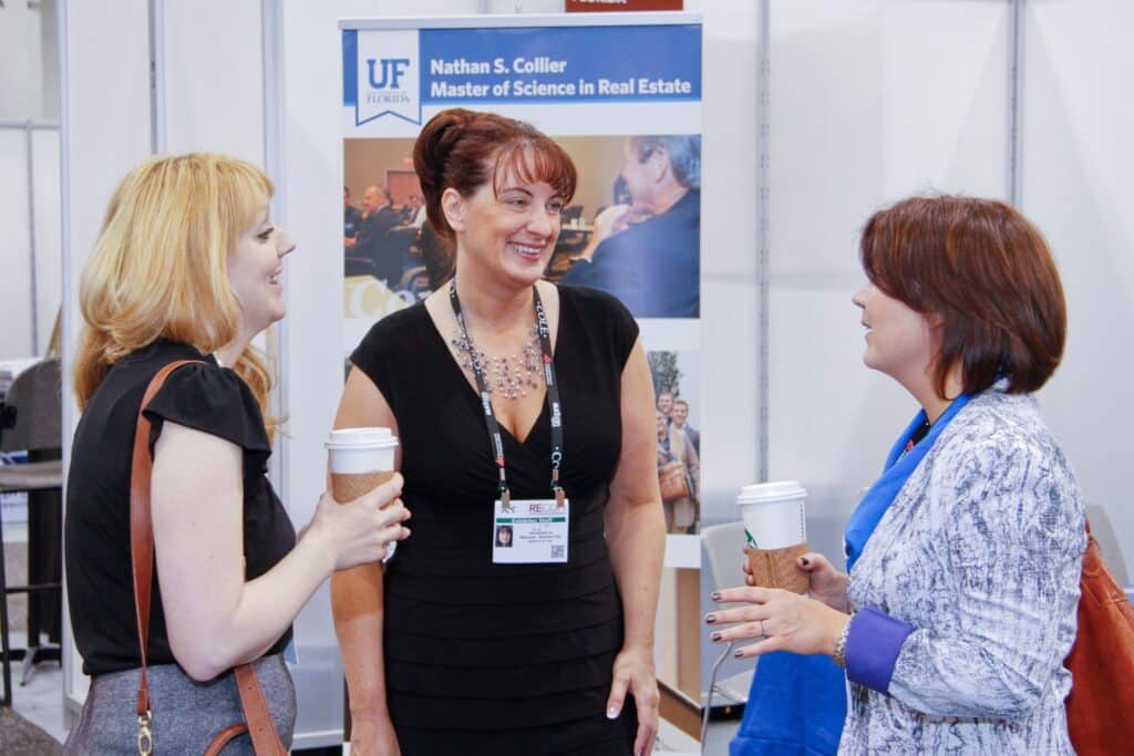 group of three women talking at a trade show booth